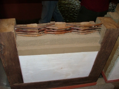Stěna zateplená dřevěnou štěpkou. Skladba z vnitřní strany (vápenný nátěr, hliněná omítka jemná a hrubá, výplet z vrbového proutí mezi dřevěnými sloupky)