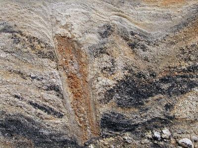 Štěrkovna Dřenice u Chebu. Pestře zbarvené vltavínonosné štěrkopísky vildštejnského souvrství pliocenního stáří (cca 2 mil. let). Červené zbarvení sedimentu je způsobeno průsaky železa, černé pak manganem. Na profilu je zachycen tzv. mrazový klín.