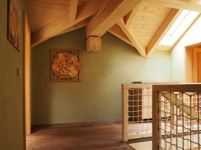 Horní schodišťová hala s hliněnou sytě zelenou omítkou. V interiéru jsou umístěny dřevěné obrazy od pana Patřičného (www.patricny.com).