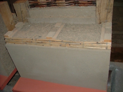 Stěna zateplená dřevěnou štěpkou. Skladba z venkovní strany (vápenná omítka na rákosové rohoži, dřevění sloupky s výpní dřevěné štěpky)